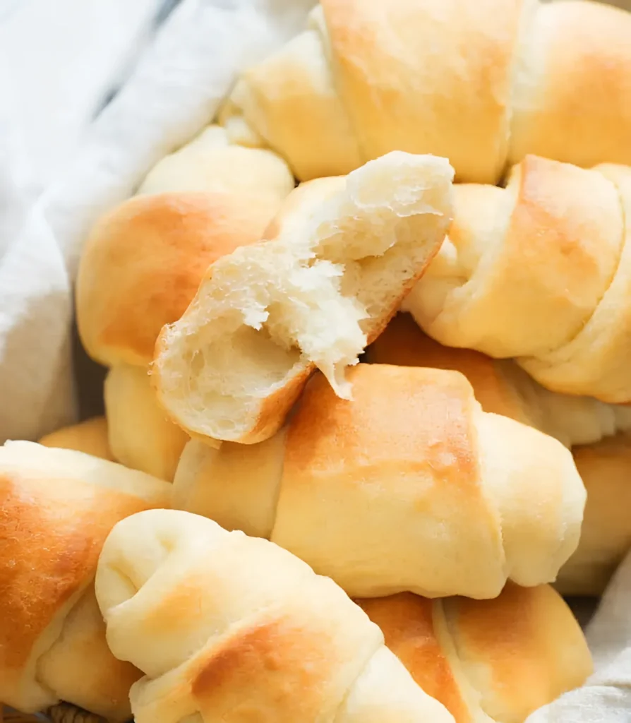 Fluffy homemade crescent rolls with a soft airy interior torn open in a basket showing light texture