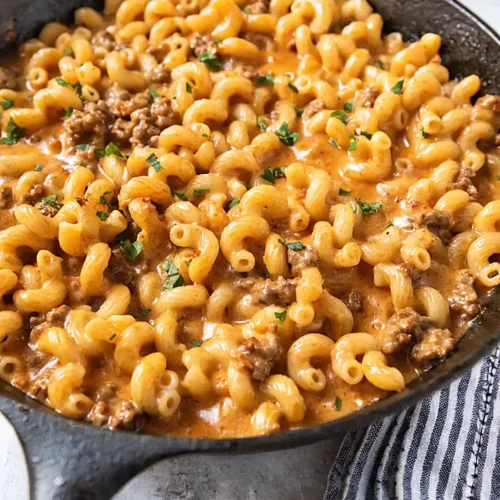 Homemade hamburger helper in a cast iron skillet with creamy cheese sauce, ground beef, and elbow macaroni