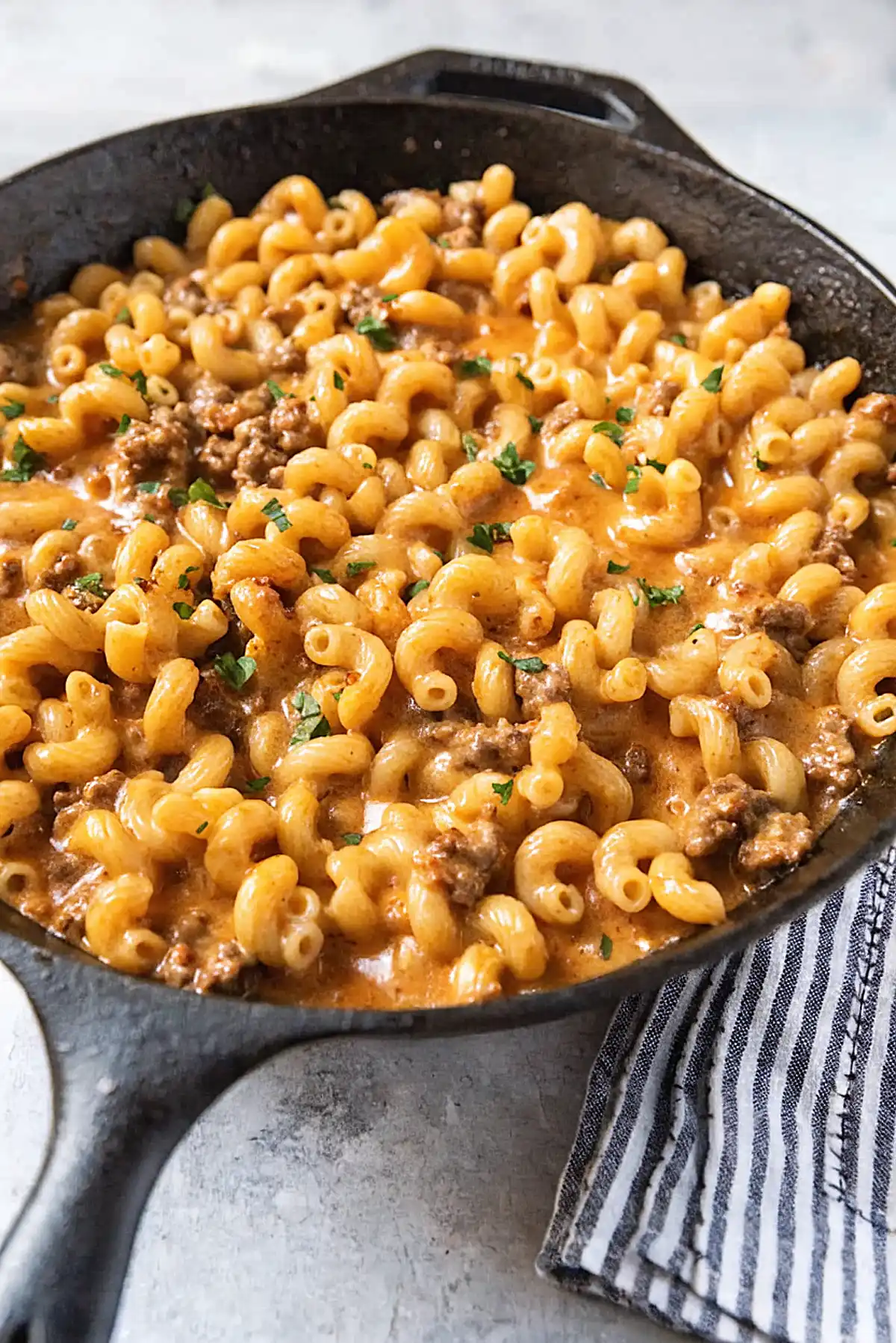 Homemade hamburger helper in a cast iron skillet with creamy cheese sauce, ground beef, and elbow macaroni
