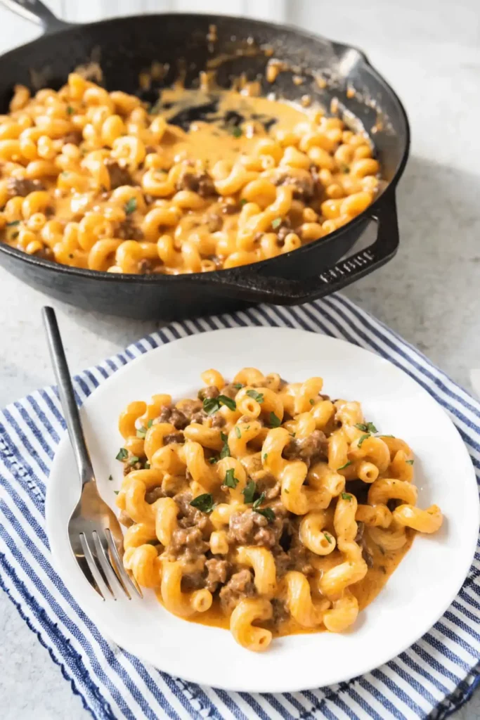 One pot homemade hamburger helper served on a white plate with creamy cheese sauce, ground beef, and elbow macaroni