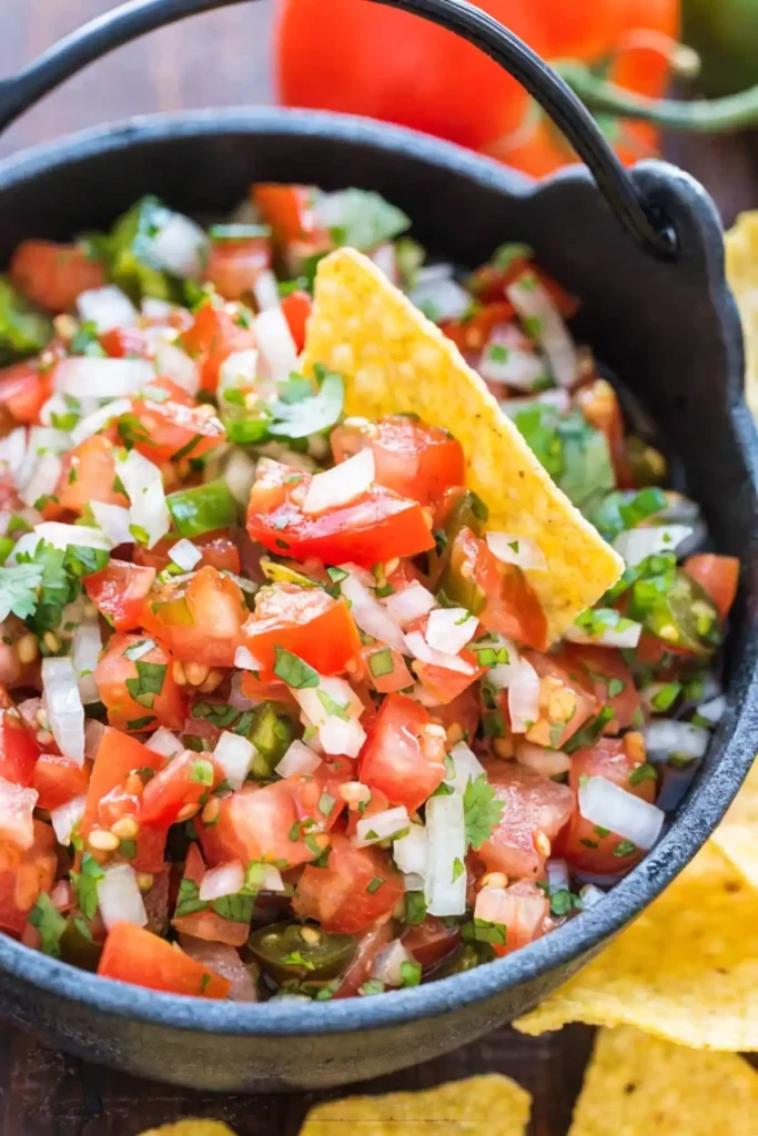 Pico de gallo in a black bowl with diced tomatoes onion cilantro and jalapeño served with tortilla chips