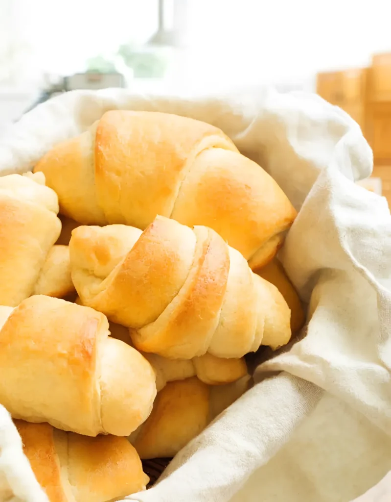 Soft homemade crescent rolls from scratch served in a cloth lined basket with golden tops and fluffy texture