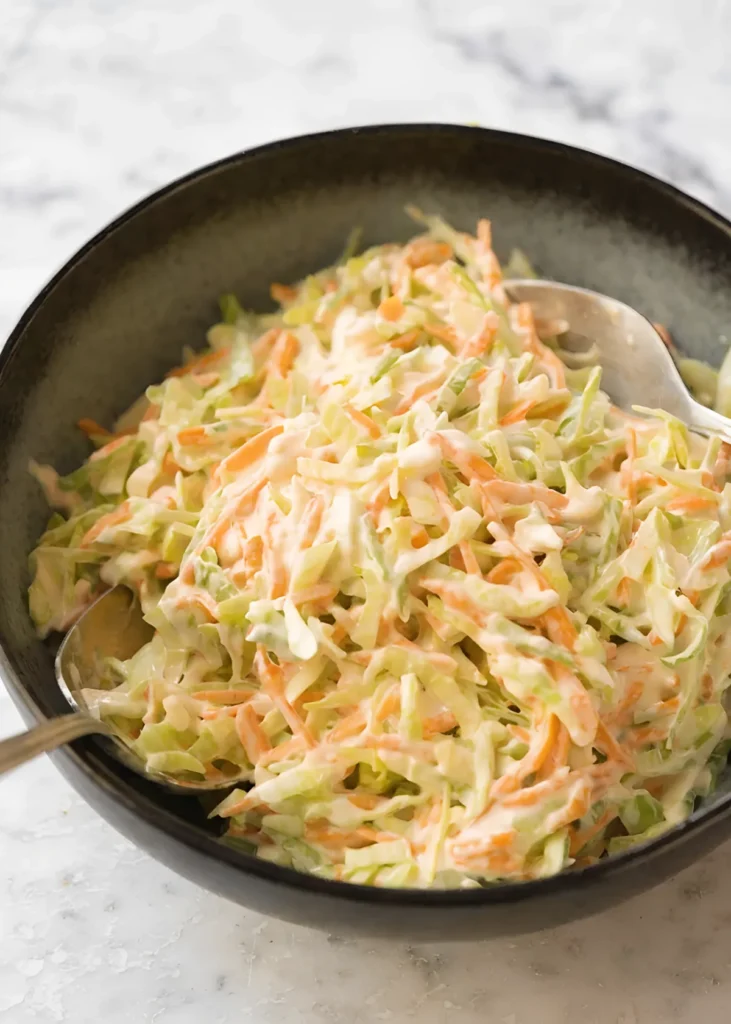 Creamy homemade coleslaw served in a black bowl with shredded cabbage, carrots, and rich coleslaw dressing.
